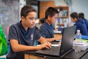 IPA student working at his computer in classroom.