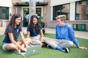 Three upper school students sitting on grass talking