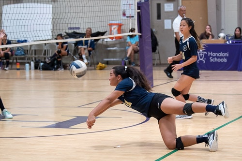 Girls volleyball player dives for the ball