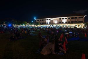 Families watch an outdoor movie on the lawn.