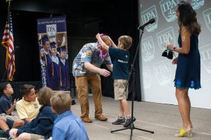 Student gives a lei to principal on stage.