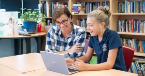 Teacher helping a student at her laptop