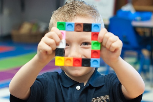 Little boy looking through a square of blocks