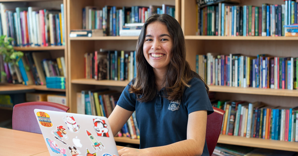 Haley Nakamura, National Merit Scholarship semi-finalist, sitting at computer