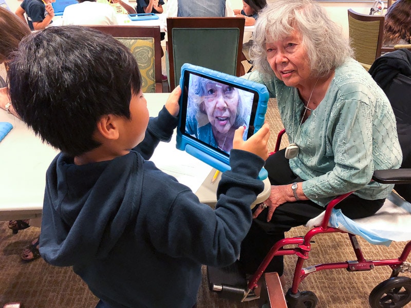 Grade 2 student takes picture of senior on iPad