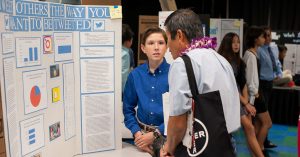 Student explaining research project to science fair judge