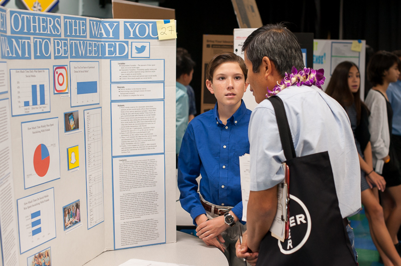 Student explaining research project to science fair judge