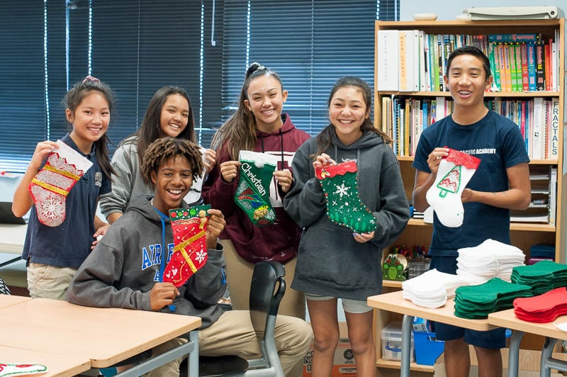 Students holding up handmade holiday stockings.