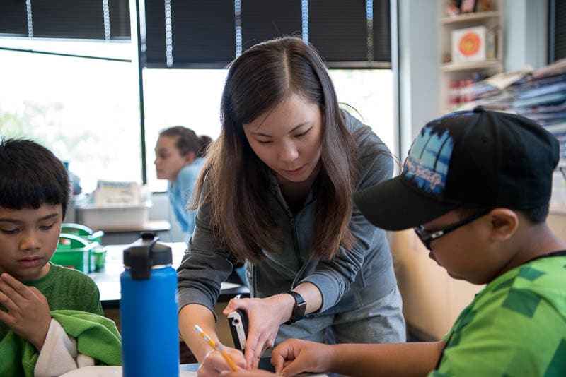 A senior student helps younger students with a math problem