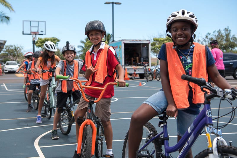 Grade 4 students in helmets and safety vests on their bikes