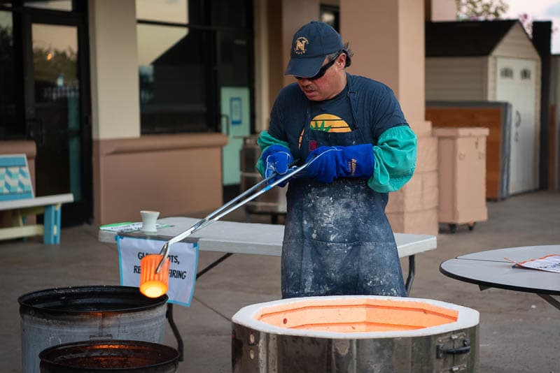 Warren Andrade removes raku fired pot from kiln