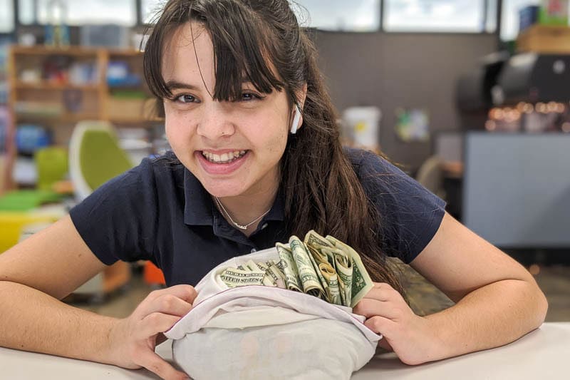 Student showing off money collected in fundraiser