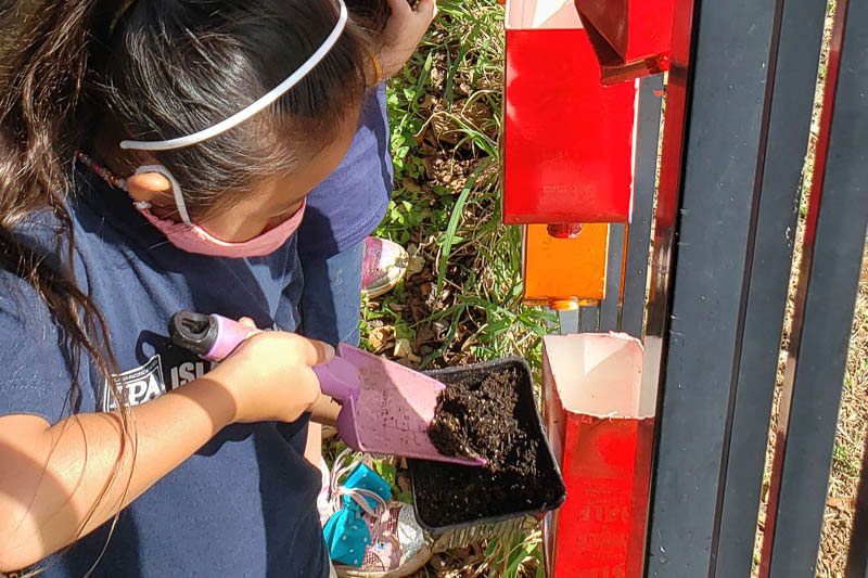 Students filling container garden with soil