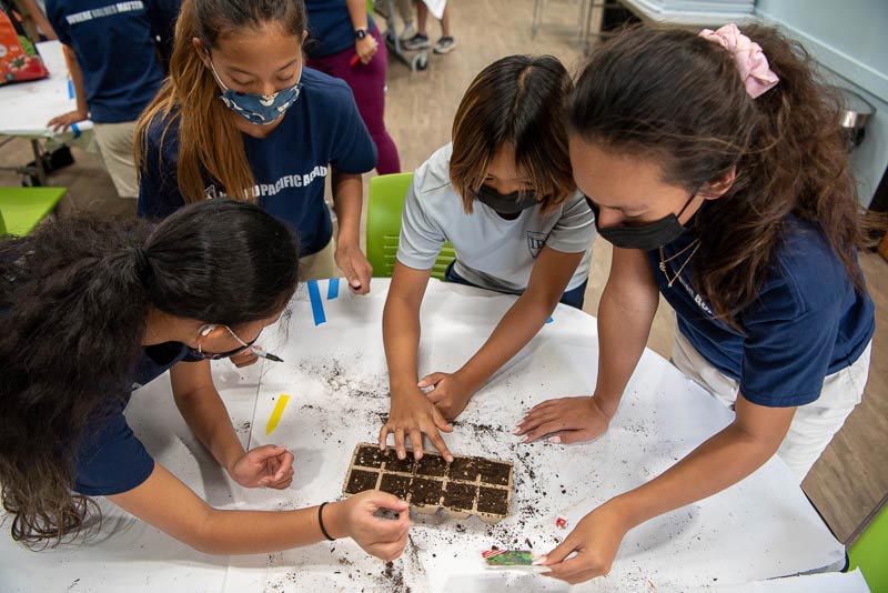 Students around a table planting seeds in soil