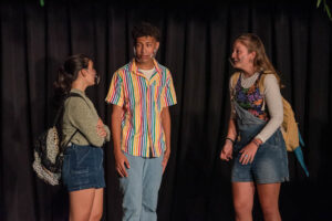 Three students acting out a scene on stage.