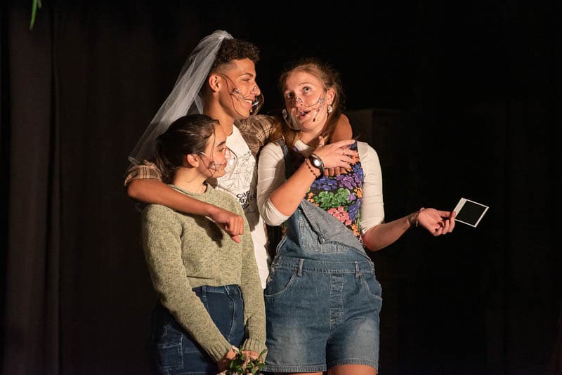 Three students acting out a scene on stage in the play, Crossroads..