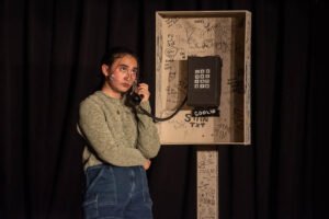 Student talks into payphone during scene in play.