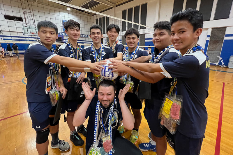 Volleyball players surrounding their coach.