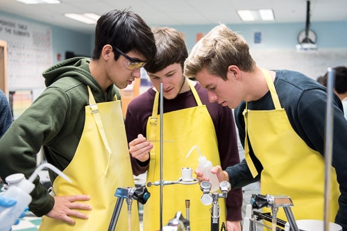 Upper School Academics IPA Students with yellow aprons working on a project