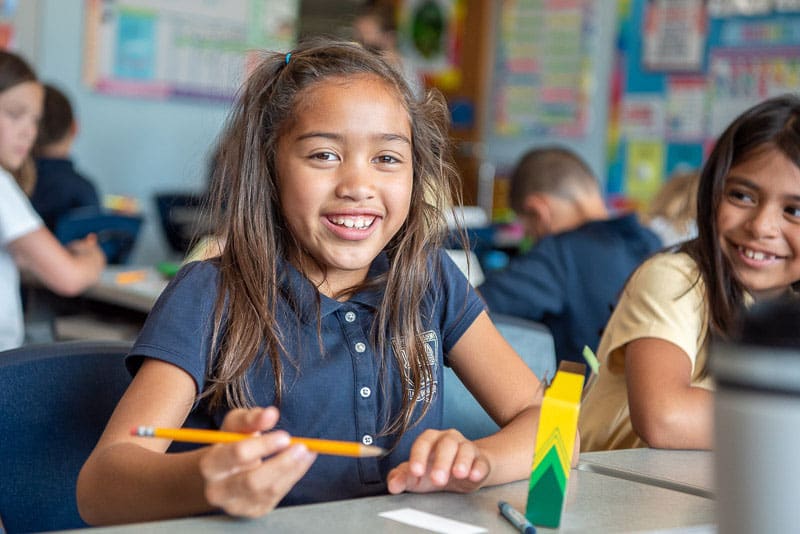 IPA students in a class room with a little girl smiling