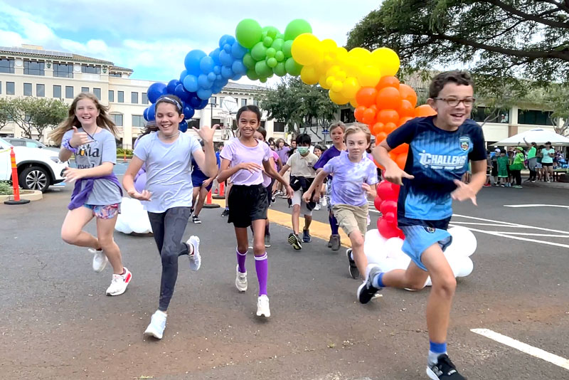 Students running through rainbow balloon arch during Color Fun-Run-a-Thon
