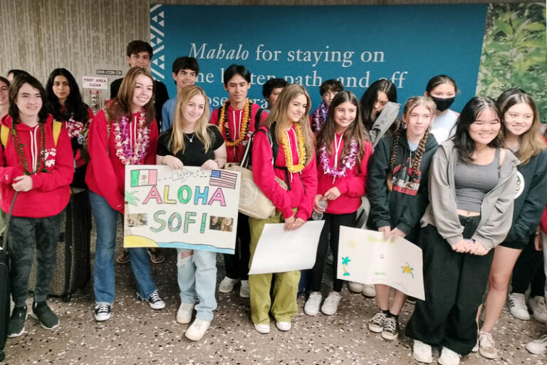 Group of IPA students with welcome signs at Honolulu International Airport.
