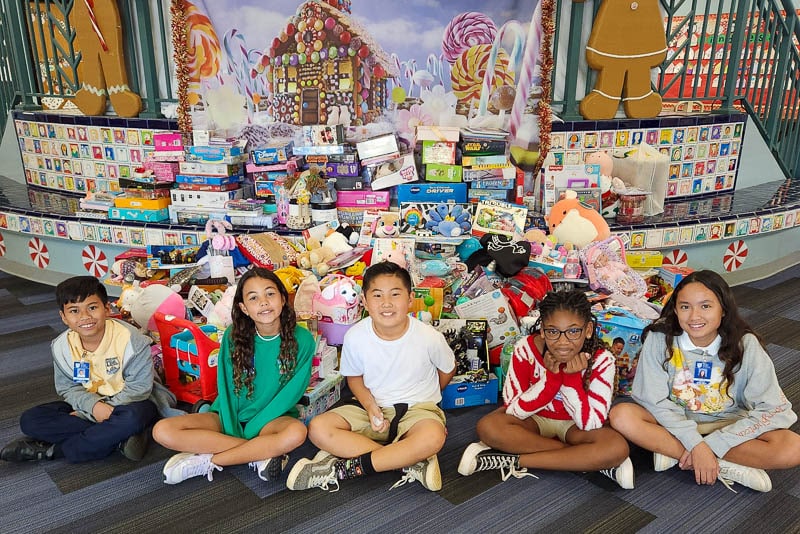 Grade 5 Student Action Committee students sitting in front of gifts.