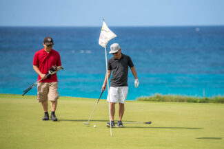 Golfers on the green with ocean backdrop